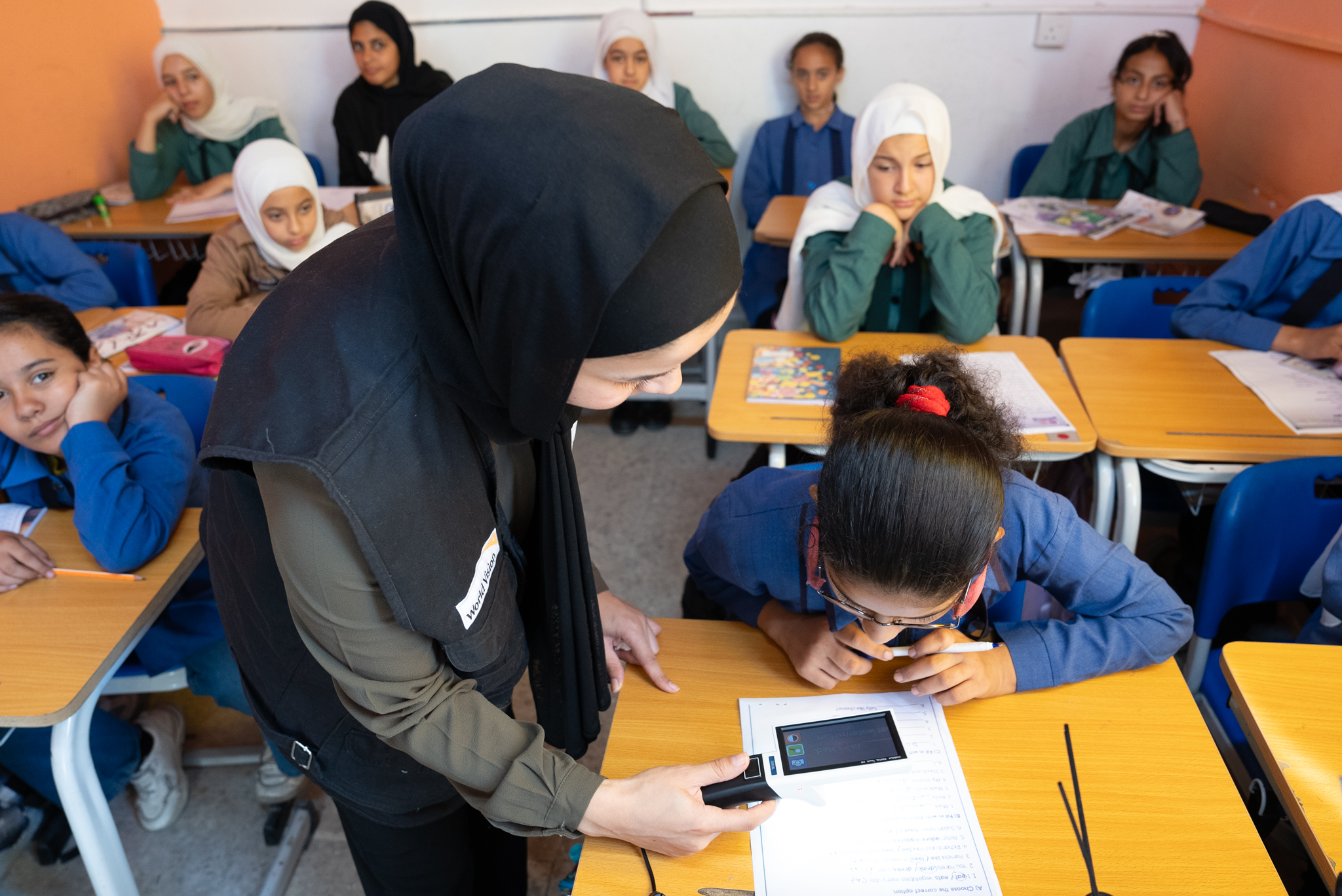 Dana* getting assistance from her teacher using the digital magnifier World Vision Syria Response, Joanna Zreineh