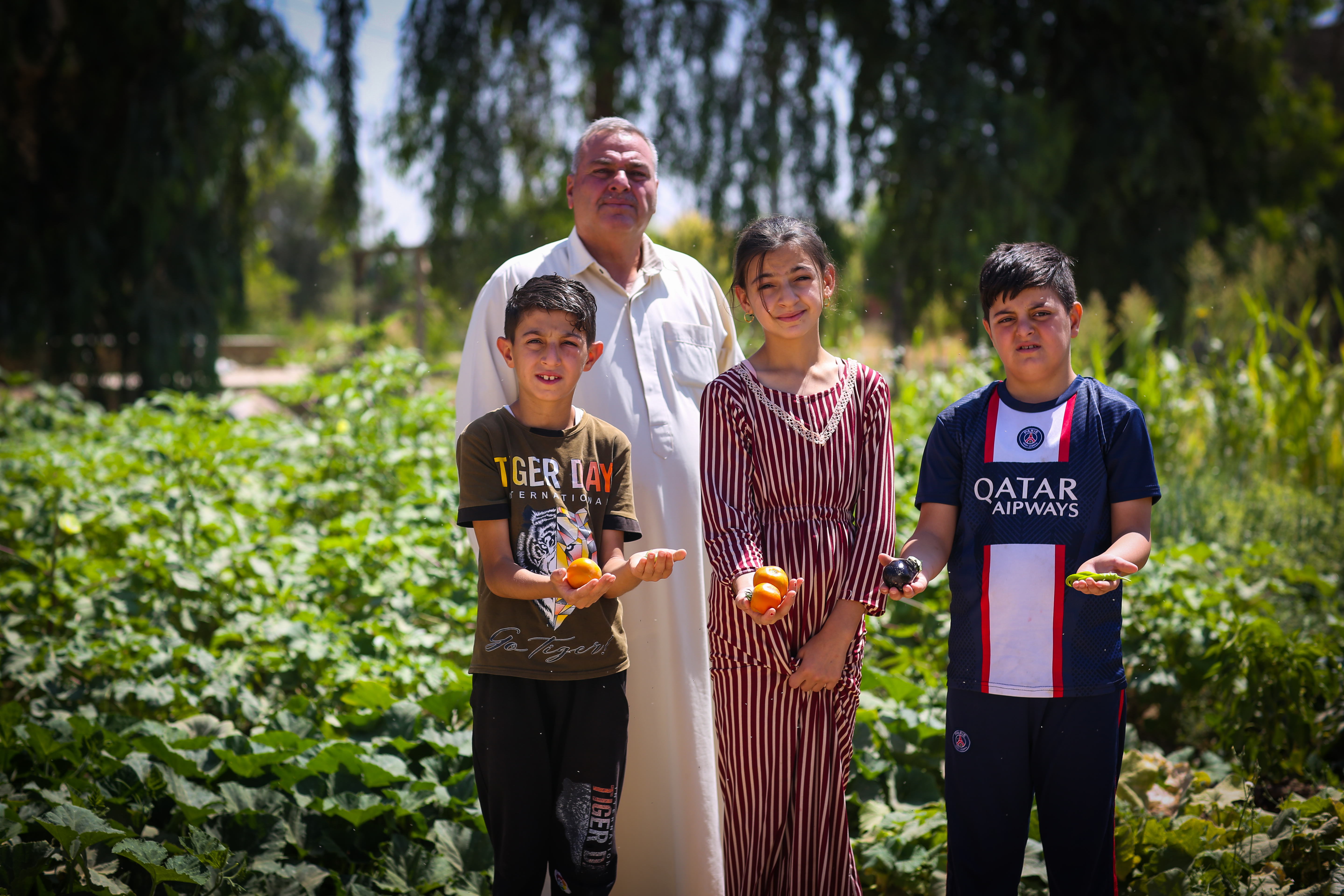 Hazim and grandchildren with fruit from their farm