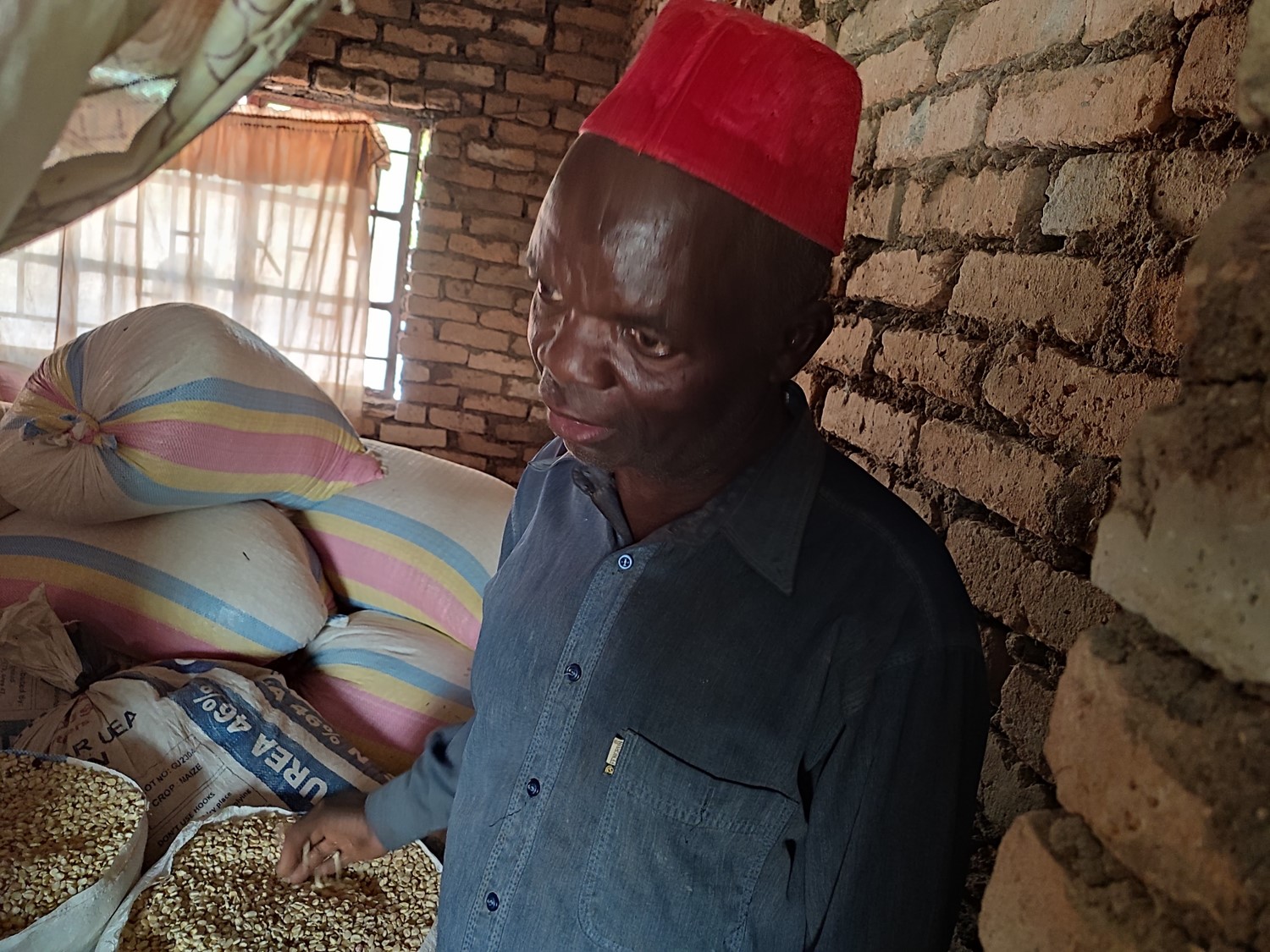 M'baya, a member of the Chemba Fish Farming Cooperative showing bags of  maize he bought for his family after selling fish.