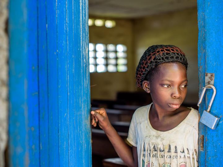 A young girl stands at her school in DRC