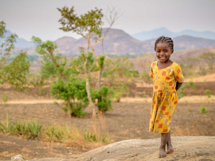A girl in Malawi stands in a field