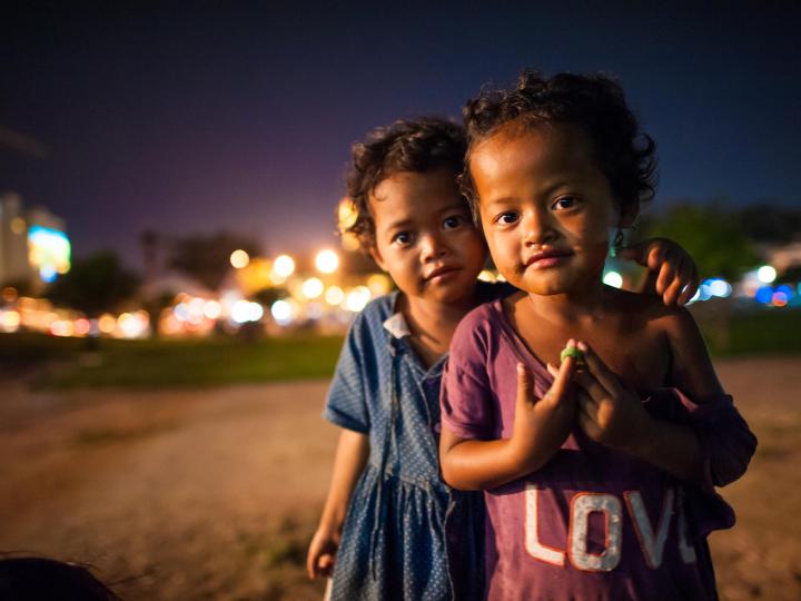 Two young Khmer children stand in the street