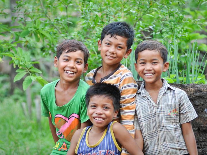Four Khmer boys smiling at camera standing in garden