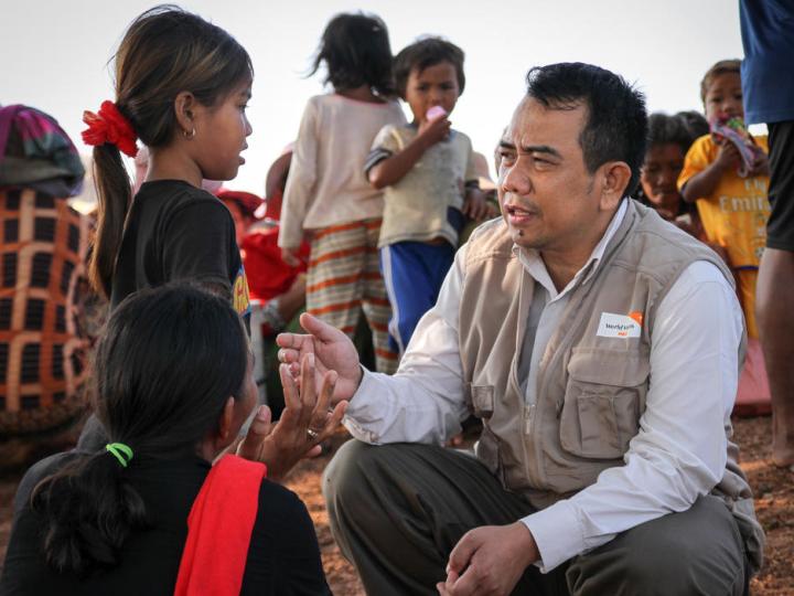 World Vision Cambodia staff member listening to flood affected child from rural village, Cambodia
