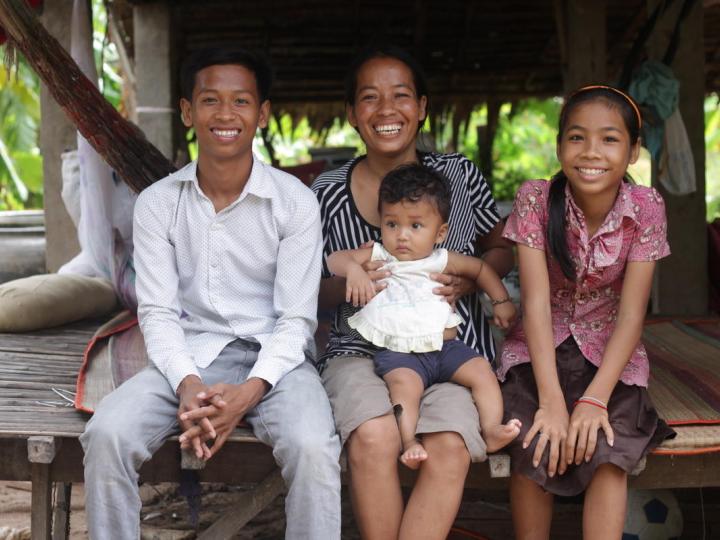 Khmer family with mum and three siblings sit together smiling, Cambodia.