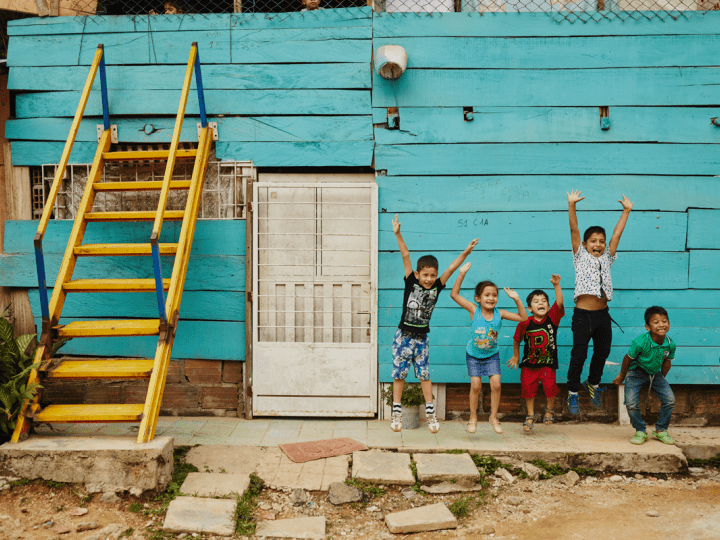 Children jumping upfront of blue wall