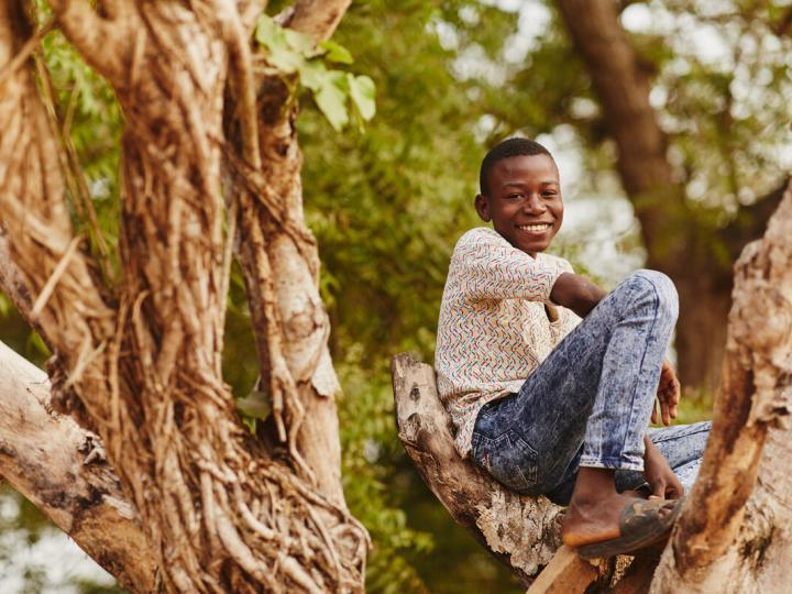 Boy climbing a tree in Ghana