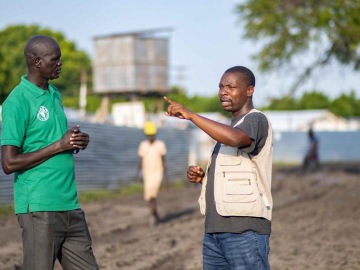 WV staff speaks to FAO staff in a field