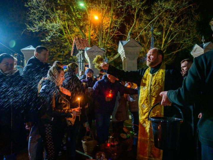 priest sprinkles holy water on crowd at easter mass