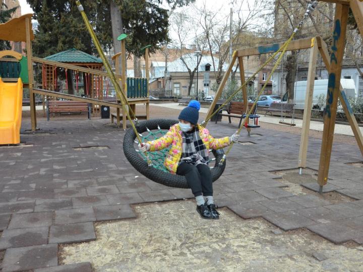 child sits on swing at an empty playground